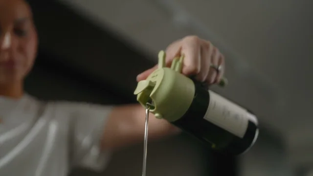 Oil pouring from a green-lid bottle in a brand demonstration; a different variant from the black bottle in the buying guide.